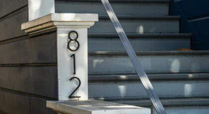 Close view of house stairs featuring the number 812 and a sleek metal handrail.