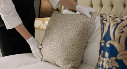 Elegant hotel bedding arrangement by a professional housekeeper in uniform.