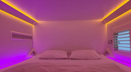 Cozy capsule hotel room with vibrant ambient lighting and minimalistic design.