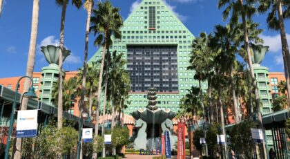 Iconic Swan Hotel at Walt Disney World in Kissimmee, FL with lush palm trees and clear skies.