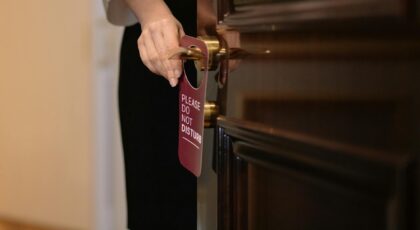 Close-up of a hand placing a 'Do Not Disturb' sign on a hotel door, illustrating privacy and service.