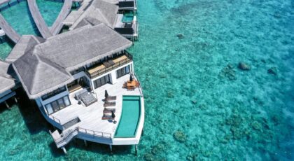 Stunning aerial view of luxury overwater villas in a tropical resort with turquoise waters.