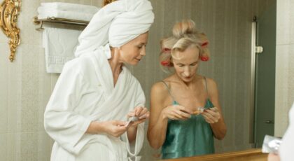 Two women in bathroom robes and curlers, ready for a spa session, exuding calmness.