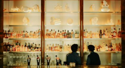 Elegant bar setting with illuminated shelves, a variety of bottles, and staff in Brussels.