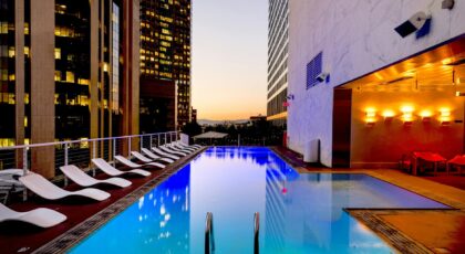 Elegant rooftop pool with cityscape backdrop at sunset, reflecting urban luxury.