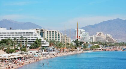 Scenic view of Eilat's coastal hotels and beach with distant mountains.
