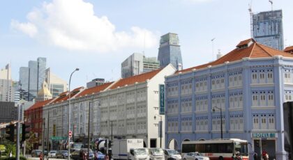 Vibrant city scene in Singapore featuring historic buildings, moving vehicles, and clear blue sky.