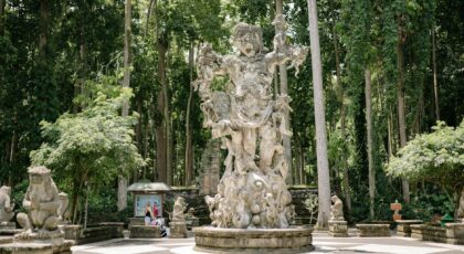 A detailed stone sculpture surrounded by tall trees in a serene park, ideal for tourism visuals.