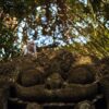 A monkey sitting on an ornate sculpture in Ubud's lush monkey forest.