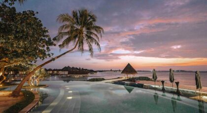 Elegant beach resort with palm trees and infinity pool at sunset, perfect for a romantic getaway.