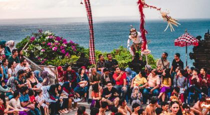 Colorful and lively traditional dance performance captivates a large outdoor audience by the sea.