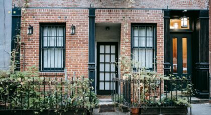 A charming brick townhouse facade with potted plants and a classic black door.