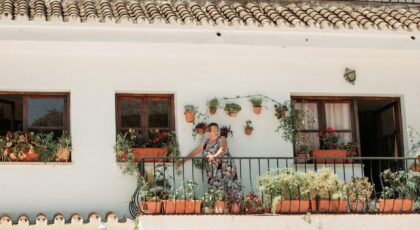 A vibrant Spanish balcony in Mijas, adorned with colorful potted plants and a woman enjoying the view.
