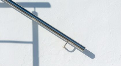 Minimalist steel railing casting a shadow on a smooth white wall, capturing simplicity.