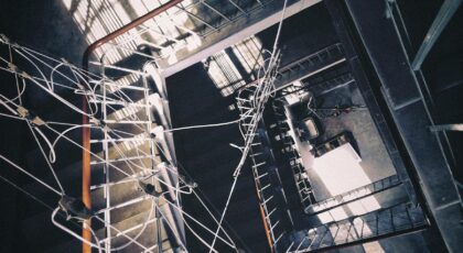 Aerial view of an industrial stairwell with intricate cable arrangement and dramatic shadows.