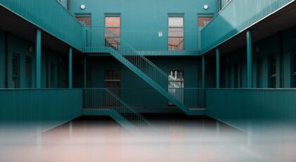 Modern interior view of a blue apartment complex featuring staircases and doors.