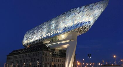 Illuminated Havenhuis in Antwerp, Belgium, showcasing modern architecture at dusk.