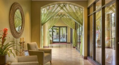 Luxurious hotel hallway featuring elegant green drapes and cozy seating area with warm lighting.