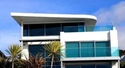 Sleek modern house with glass facade in Poole, UK under blue sky.