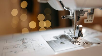 Detailed view of a sewing machine needle and parts with bokeh background, showcasing precision engineering.