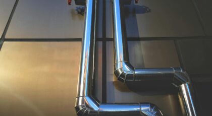 Close-up view of industrial steel pipes with valves on a metallic background, showcasing architecture.