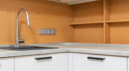 Empty modern kitchen interior featuring a stainless steel sink and wooden cabinet design.