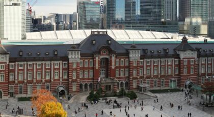 View of historic Tokyo Station surrounded by modern skyscrapers under clear autumn skies.