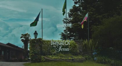 Entrance to Bangalos da Serra with national flags and lush greenery.