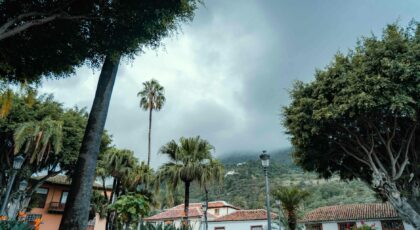 Explore the lush greenery and traditional architecture of Icod de los Vinos, Spain under a cloudy sky.
