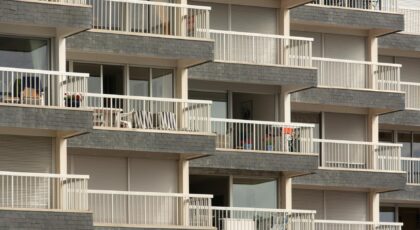 Modern apartment building facade with multiple balconies, showcasing urban architecture.