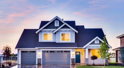 Beautiful two-story house with illuminated windows and garage at dusk.