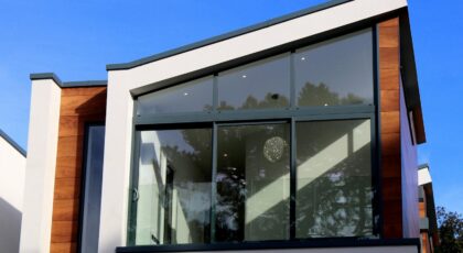 Contemporary house in Poole, UK featuring a sleek design with large glass windows and wood paneling.