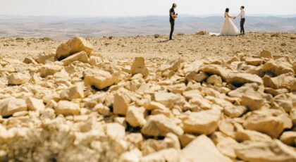 A romantic wedding photoshoot in a rocky desert with a couple and a musician.