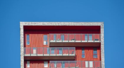 Minimalist design of a modern red building facade against a clear blue sky.