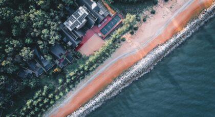 Aerial shot of villas by a beautiful shoreline with forest and beach.