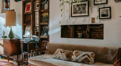 Interior of stylish living room with comfortable couch placed near shelf with collection of vintage vinyl records and wooden cabinet decorated with classic table lamp