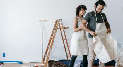 A couple in aprons getting ready to renovate their home, showing teamwork and joy.