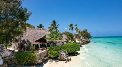Beautiful tropical beach resort in Zanzibar, Tanzania, with thatched huts, palm trees, and turquoise waters.