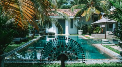 A tranquil tropical villa with a swimming pool surrounded by lush palm trees.