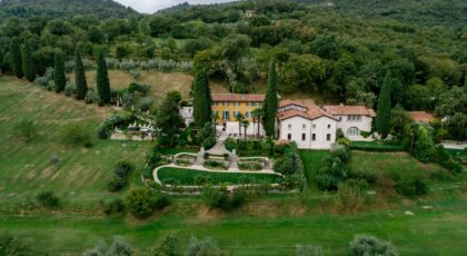 A stunning aerial view of a Tuscan villa surrounded by lush greenery and hills.