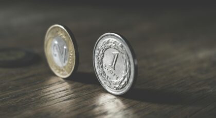 Close-up of Polish zloty coins standing on a wooden table, showcasing metal reflections.