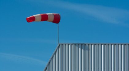 A red and white windsock on a corrugated rooftop under a clear blue sky.