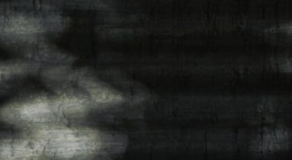 Close-up of a dark metal surface with abstract shadows and textures.