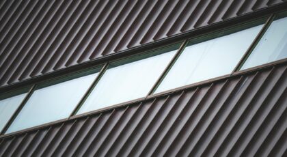High-angle view of a modern building facade with metal panels and diagonal windows. Ideal for architectural themes.