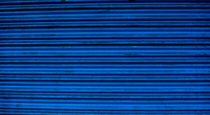 Close-up of a textured blue metal surface showing horizontal lines and patterns, ideal for backgrounds.