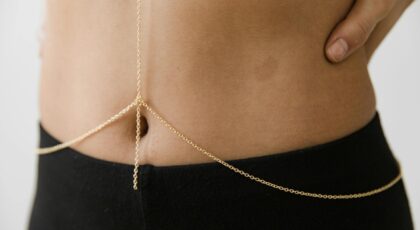 Close-up of a gold body chain on a woman's waist, adding chic elegance.