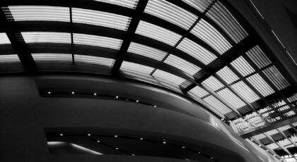 Black and white photo capturing a modern architectural ceiling with curved structural elements.