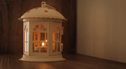 A cozy decorative lantern casting a warm glow on a wooden surface indoors.