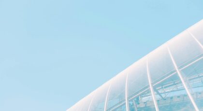 Low angle view of a modern glass building under a clear blue sky, showcasing architectural elegance.