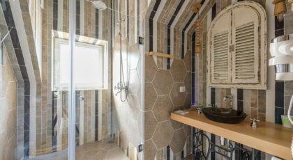 Beautifully designed bathroom featuring stylish tiles, glass shower, and unique sink area.